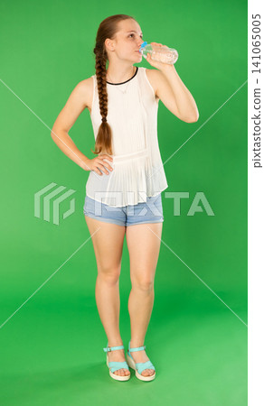 Teenage girl drinking water from plastic bottle on green background. Chroma key compositing Teenage girl drinking water from plastic bottle on green background. Chroma key compositing 141065005