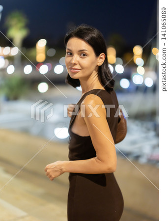 Woman walking along coastal promenade at night in Barcelona 141065089