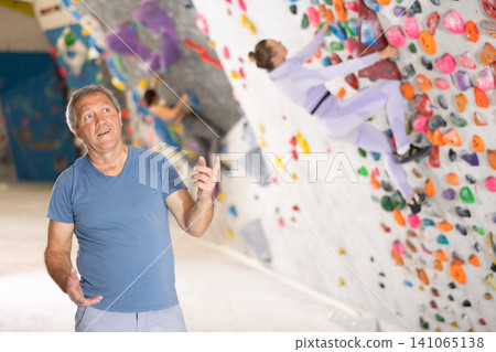 Adult man posing on climbing wall Adult man posing on climbing wall 141065138