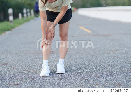 Young adult female runner with knee pain from ACL injury or patellofemoral syndrome. woman having joint ache, ligament tear or patellar tendinitis during running. Sports medical and healthcare concept Young adult female runner with knee pain from ACL injury or patellofemoral syndrome. woman having joint ache, ligament tear or patellar tendinitis during running. Sports medical and healthcare concept 141065407