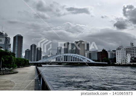 A view of the tower apartment buildings in Tsukuda, Chuo Ward, across the Eitai Bridge from the Sumida River Terrace, accompanied by rain clouds. A view of the tower apartment buildings in Tsukuda, Chuo Ward, across the Eitai Bridge from the Sumida River Terrace, accompanied by rain clouds. 141065973