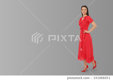 Model stands in red dress on gray background for a design mockup Model stands in red dress on gray background for a design mockup 141066051