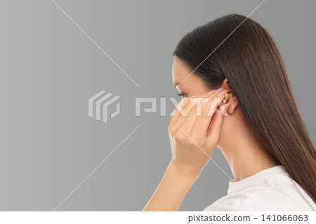 Woman adjusts wireless earbuds in a light gray backdrop Woman adjusts wireless earbuds in a light gray backdrop 141066063