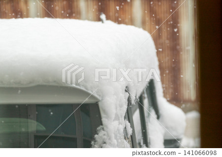 Close-up of a car with snow piled on the roof due to heavy snowfall, and the danger of falling snow. Close-up of a car with snow piled on the roof due to heavy snowfall, and the danger of falling snow. 141066098