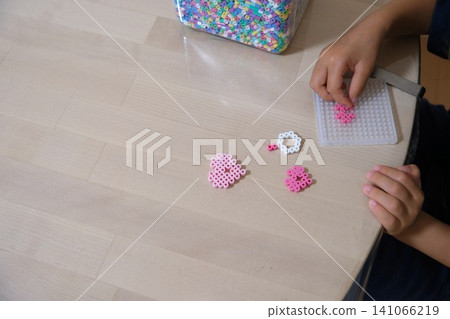 A child's hands playing with iron beads on a table A child's hands playing with iron beads on a table 141066219