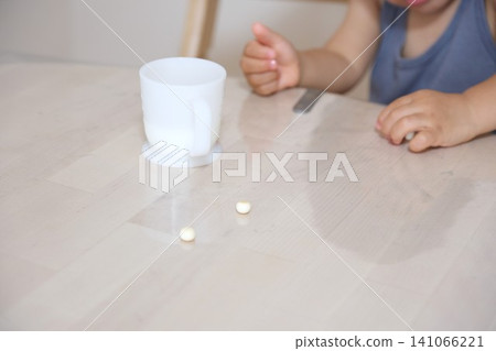 A toddler's hands eating a baby biscuit snack and milk. A toddler's hands eating a baby biscuit snack and milk. 141066221