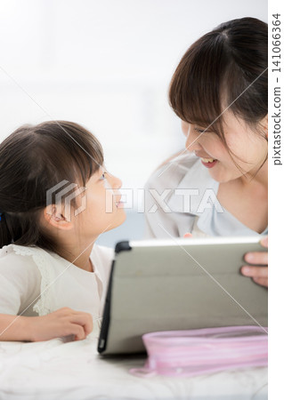 「我明白我在學什麼了！」一位母親和她的小學生女兒一起用平板電腦學習，她們高興地對視了一眼。 141066364