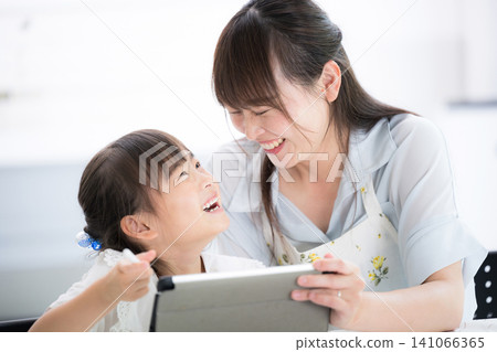「我明白我在學什麼了！」一位母親和她的小學生女兒一邊用平板電腦學習，一邊高興地對視著。 141066365
