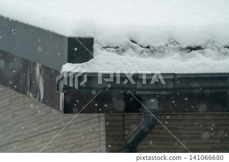 現代房屋的屋頂和雨水槽被厚厚的積雪覆蓋的特寫。 現代房屋的屋頂和雨水槽被厚厚的積雪覆蓋的特寫。 141066680