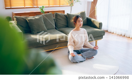 Happy young Asian woman practicing yoga and meditation at home Happy young Asian woman practicing yoga and meditation at home 141066998