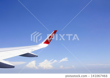 Airplane wing with red logo flying in clear blue sky 141067468