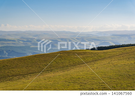 Layers of green mountains and hills in the haze during sunset. Panoramic View of Green hills and Meadow. 141067560