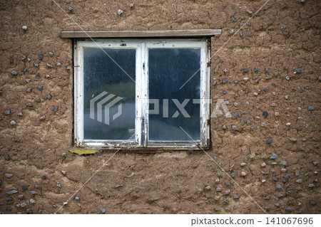 Weathered White Window Set in Rustic Mud Wall of Old Rural Building With Pebble Texture Weathered White Window Set in Rustic Mud Wall of Old Rural Building With Pebble Texture 141067696