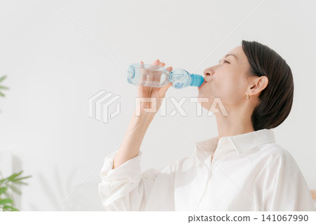 一位女士正在喝冰檸檬水。 一位女士正在喝冰檸檬水。 141067990