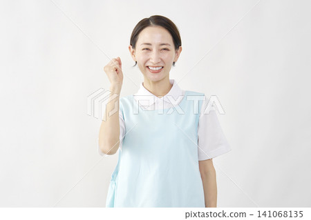 Female caregiver makes a victory pose against a white background. Female caregiver makes a victory pose against a white background. 141068135