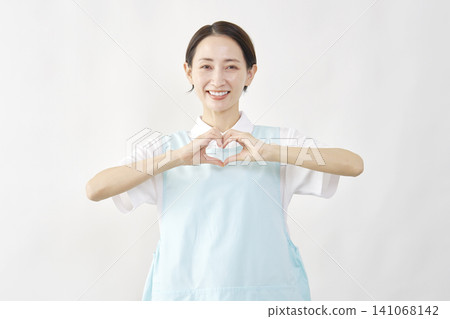 一位女護理員在白色背景前擺出心形姿勢 141068142