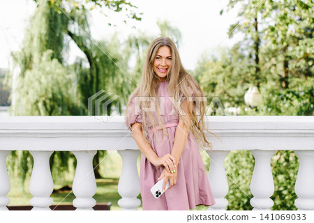 Beautiful Woman In Pink Summer Dress Holding Smartphone 141069033