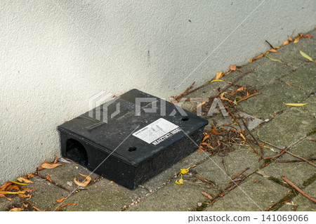 Black Rodent Bait Station Placed Along Building Wall for Safe Outdoor Pest Control and Monitoring System Black Rodent Bait Station Placed Along Building Wall for Safe Outdoor Pest Control and Monitoring System 141069066