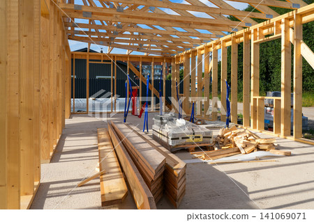 Timber Frame House Interior Under Construction with Lumber, Roof Trusses and Utility Installation Work Timber Frame House Interior Under Construction with Lumber, Roof Trusses and Utility Installation Work 141069071