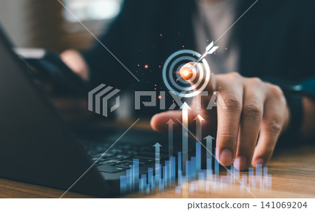 Businessperson touching virtual target icon with growing financial graph chart. Concept of business goal achievement, marketing strategy, investment success, and objective Businessperson touching virtual target icon with growing financial graph chart. Concept of business goal achievement, marketing strategy, investment success, and objective 141069204