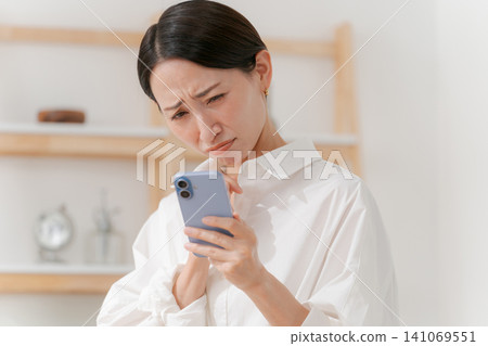 A woman who is depressed when she sees a smartphone A woman who is depressed when she sees a smartphone 141069551
