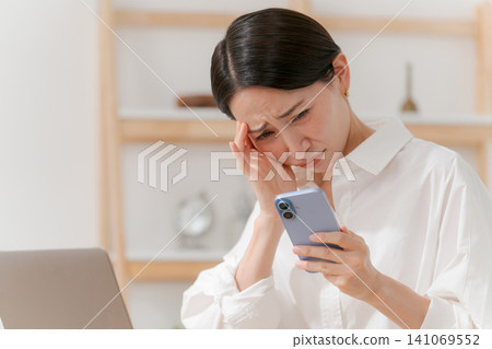 A woman who is depressed when she sees a smartphone A woman who is depressed when she sees a smartphone 141069552