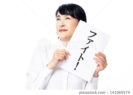 一位身穿白襯衫的中年婦女抬起頭，瞇著眼睛，手裡拿著一張紙，上面寫著「戰鬥」。 141069574