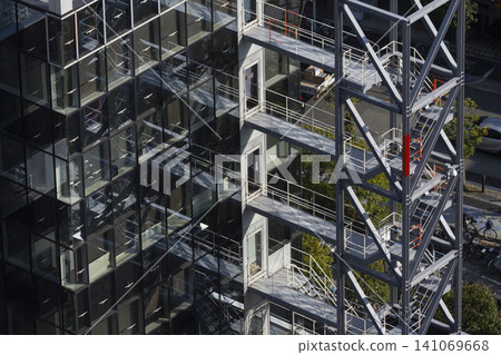 The exterior of the glass-walled building features an emergency staircase and connecting walkway. 141069668