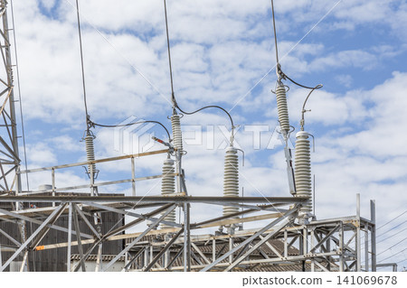 電力變電站設備的絕緣體排列在多雲的藍天下。 141069678