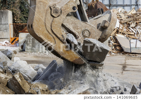 Demolition site where concrete blocks are being crushed with heavy machinery attachments. Demolition site where concrete blocks are being crushed with heavy machinery attachments. 141069685