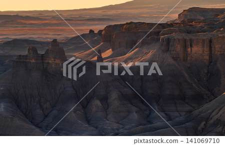 Beautiful tranquil landscape showing vast desert canyon with dramatic rock formations illuminated by warm golden light of sunset over majestic mountains of utah Beautiful tranquil landscape showing vast desert canyon with dramatic rock formations illuminated by warm golden light of sunset over majestic mountains of utah 141069710