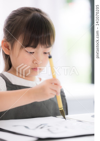 一位日本小學生正在專心練習書法，用毛筆書寫文字。 141070205