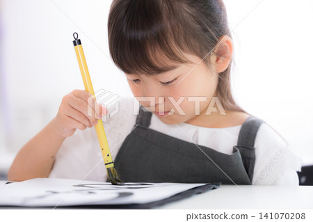 一位小學生專注地練習書法,用毛筆書寫漢字。鏡頭特寫。日本兒童學習書法,表情嚴肅。 一位小學生專注地練習書法,用毛筆書寫漢字。鏡頭特寫。日本兒童學習書法,表情嚴肅。 141070208