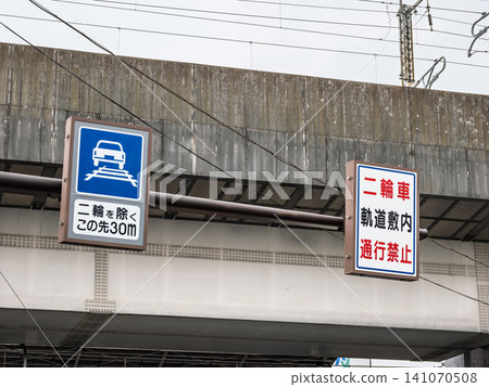 A sign indicating that passage is permitted within the Toden Arakawa Line tracks and a warning sign are installed above the road. A sign indicating that passage is permitted within the Toden Arakawa Line tracks and a warning sign are installed above the road. 141070508
