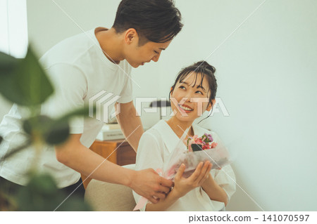 A woman receives a bouquet of flowers and looks up at the man with a smile. A woman receives a bouquet of flowers and looks up at the man with a smile. 141070597