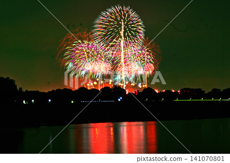 Colorful fireworks blooming in the night sky and a fantastical reflection Colorful fireworks blooming in the night sky and a fantastical reflection 141070801