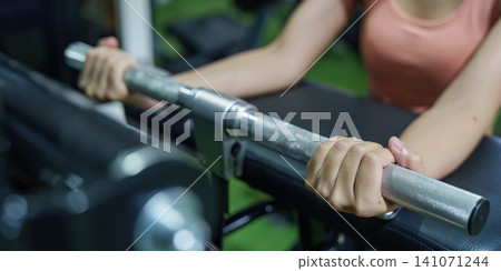 Cropped hands gripping barbell on gym machine for strength training and weightlifting Cropped hands gripping barbell on gym machine for strength training and weightlifting 141071244