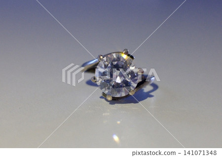 Brilliant round diamond in white gold engagement ring on a gray surface Brilliant round diamond in white gold engagement ring on a gray surface 141071348