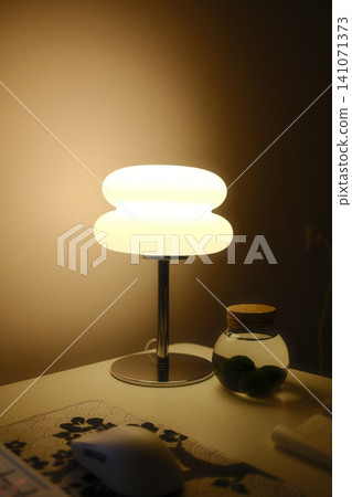 A lamp illuminates a desk with a jar of Marimo moss balls A lamp illuminates a desk with a jar of Marimo moss balls 141071373