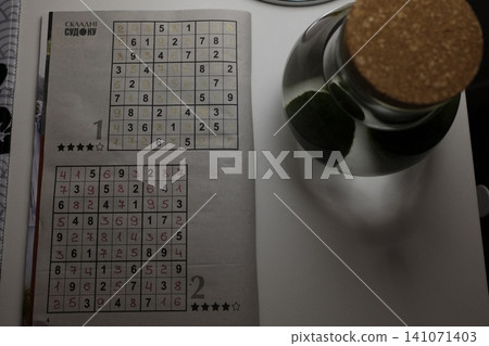 Handwritten numbers fill a Sudoku grid on a paper from a puzzle book Handwritten numbers fill a Sudoku grid on a paper from a puzzle book 141071403