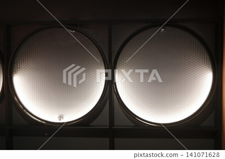 Modern, textured circular panels cast soft upward light in a dim architectural space Modern, textured circular panels cast soft upward light in a dim architectural space 141071628