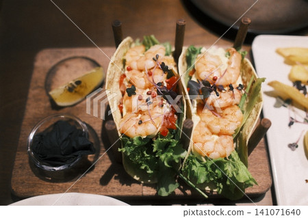 Two vibrant shrimp tacos filled with fresh lettuce and plump shrimp Two vibrant shrimp tacos filled with fresh lettuce and plump shrimp 141071640