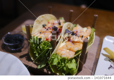Two soft tacos feature juicy shrimp, crisp lettuce, and creamy sauce Two soft tacos feature juicy shrimp, crisp lettuce, and creamy sauce 141071644