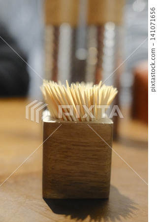 Full wooden toothpick holder on a wooden table, offering toothpicks for dental hygiene after a meal 141071656