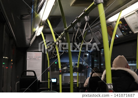 Passengers travel inside a public bus during evening hours. Passengers travel inside a public bus during evening hours. 141071687