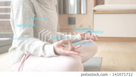 Meditating woman in light-gray turtleneck and pink sweats on yoga mat at home, with blue overlays Meditating woman in light-gray turtleneck and pink sweats on yoga mat at home, with blue overlays 141071712