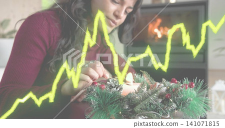 Leaning woman in burgundy knit lighting candle in table wreath at home, with yellow-green overlay Leaning woman in burgundy knit lighting candle in table wreath at home, with yellow-green overlay 141071815