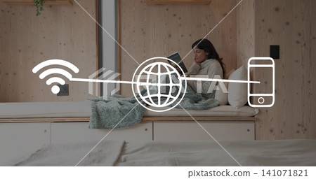 Sitting woman in sweater reading book on daybed in sleeping nook, Wi-Fi globe phone, copy space Sitting woman in sweater reading book on daybed in sleeping nook, Wi-Fi globe phone, copy space 141071821