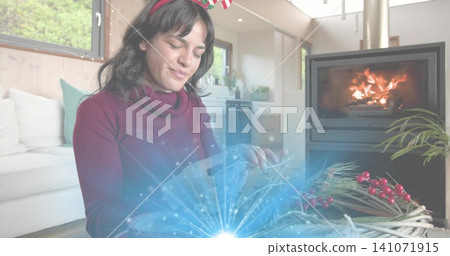 Assembling woman in burgundy sweater and festive headband crafting wreath at home with fireplace Assembling woman in burgundy sweater and festive headband crafting wreath at home with fireplace 141071915