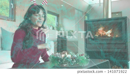 Smiling woman in striped headband reaching toward wreath on coffee table at home, with stove flame Smiling woman in striped headband reaching toward wreath on coffee table at home, with stove flame 141071922